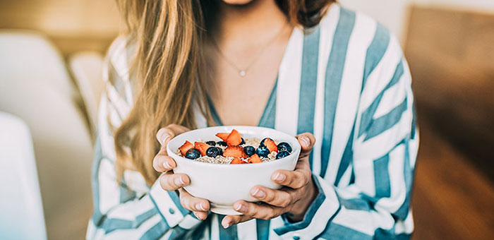 Woman eating a healthy cereal after receiving diet guidance from Oakland chiropractor