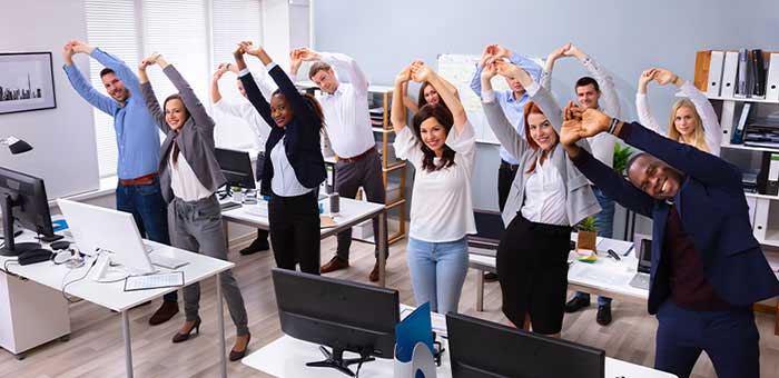 Office team stretching together under guidance of Oakland chiropractor